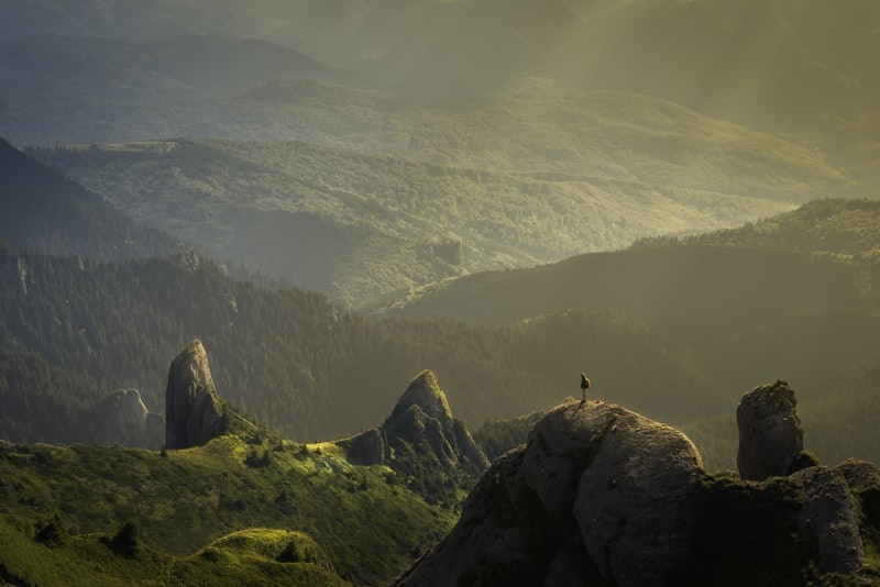 A traveler standing on a ridge at golden hour, looking out over a wide valley.