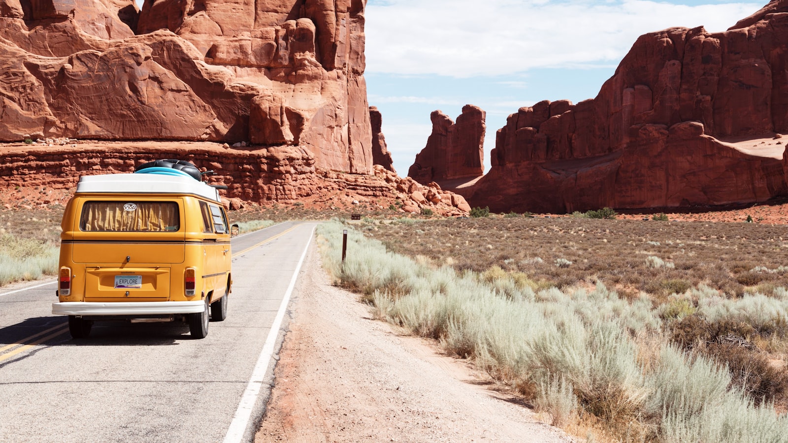 An open road curving through rolling hills toward distant mountains under a wide sky