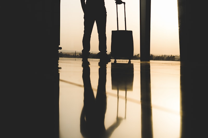 A traveler studying a paper map and notebook on a wooden table beside a packed backpack.
